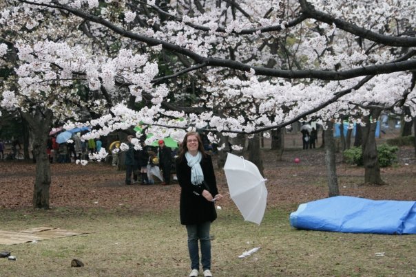 Nainen krisikkapuun alla sateenvarjo kädessä