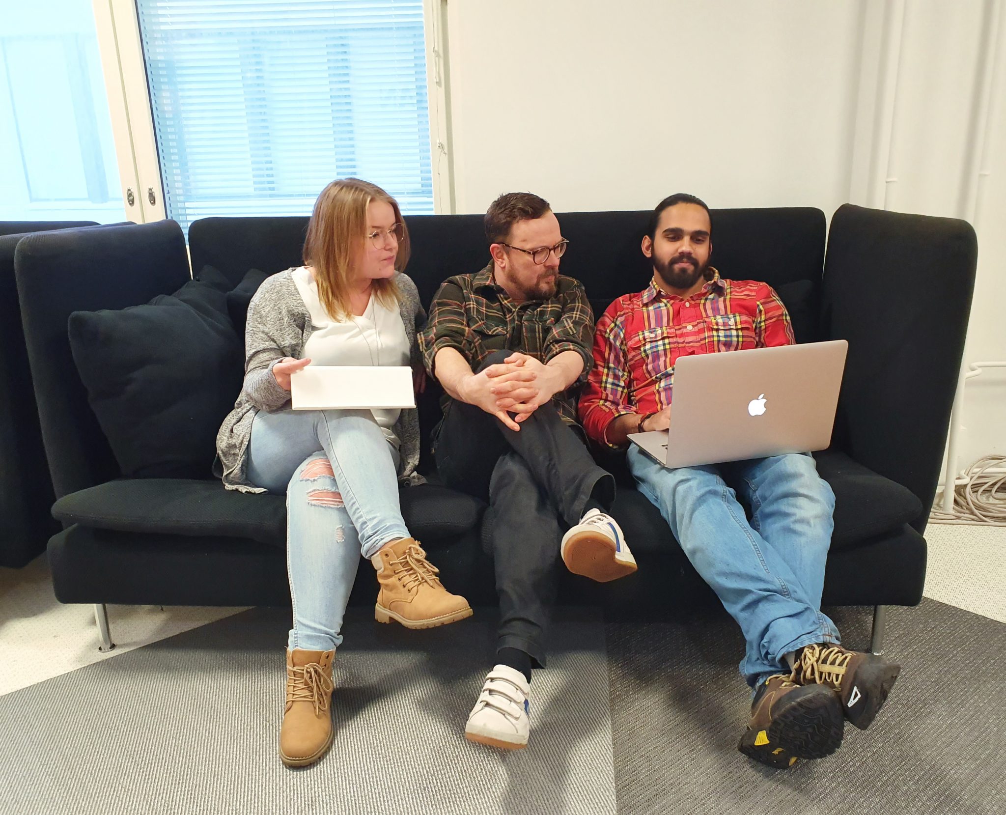 Kolme Humakin Yhteisöpedagogi (AMK) -oppilasta istuvat vierekkäin sohvalla ja katsovat sylissä olevaa kannettavaa tietokonetta.