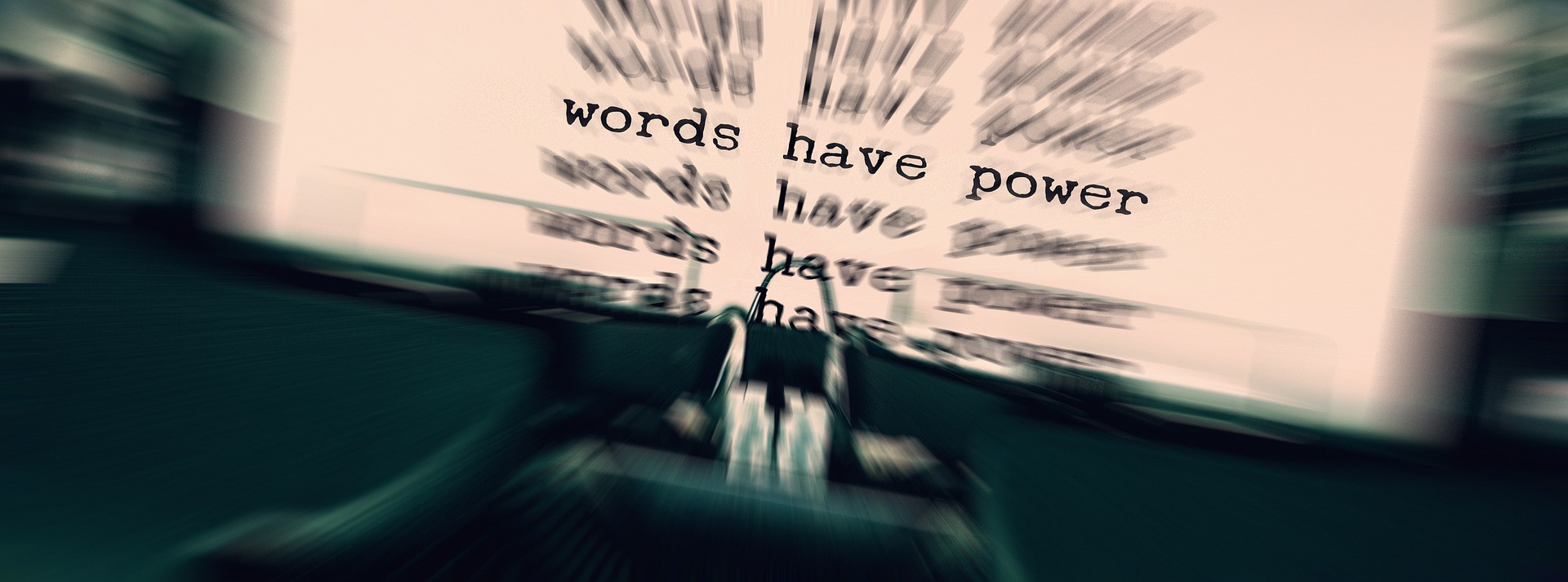 Kuvassa on kirjoituskone ja paperi, jossa lukee lause: Words have power. Sanoilla on valtaa.