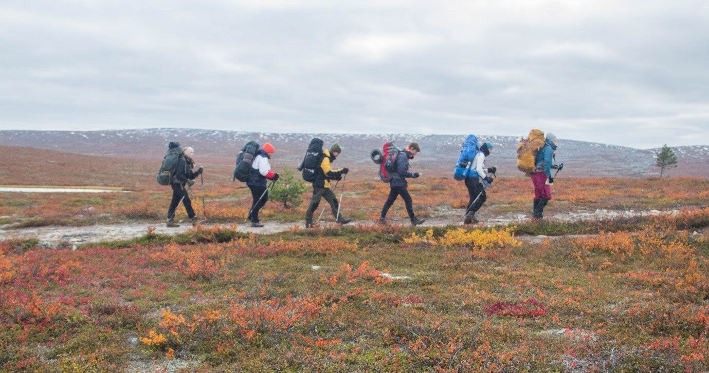 Kuusi opiskelijaa vaeltaa ruskan värittämässä pohjoisen Lapin maisemassa.