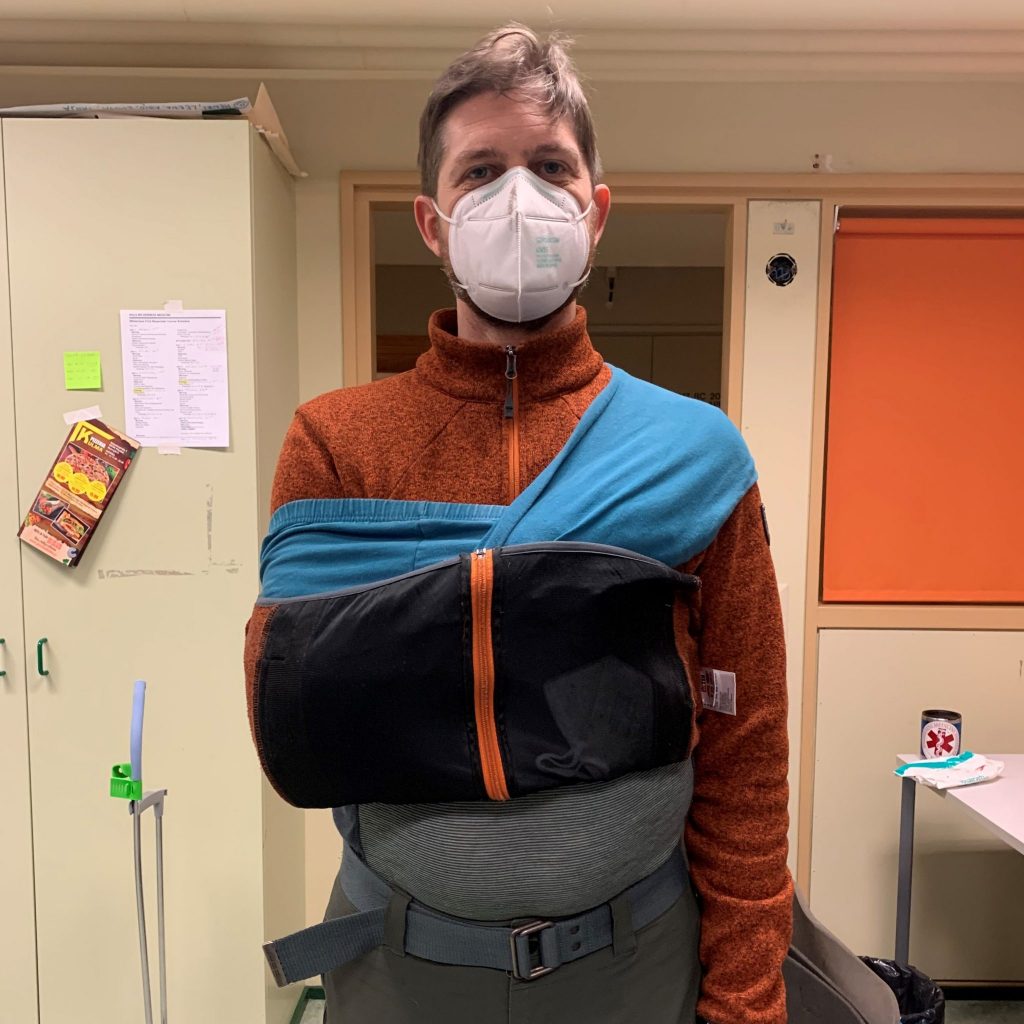 A person with a face mask having a shoulder problem and adaptive sling on it.