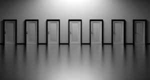 Seven similar, closed doors horizontally next to each another against a gray background.