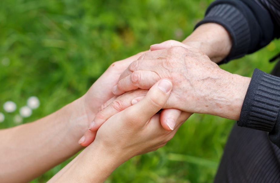 Young person's hands are holding an old person's hands.