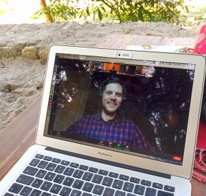 Screenshot of an online meeting with a happy looking face of a man.