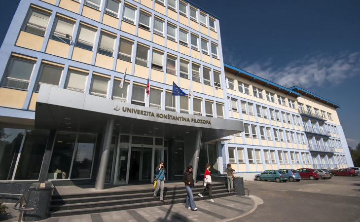 Valokuva Constantine the Philosopher University´n rakennuksesta, jonka seinässä näkyy yliopiston nimi Univerzita Konstantina Filozofa. Rakennuksessa liehuvat myös Slovakian ja EU:n liput.
