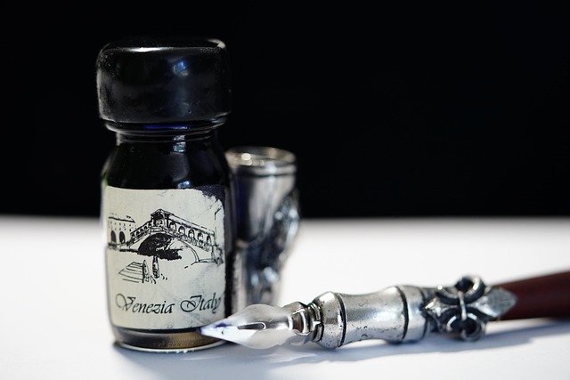 Vanhanaikainen mustepullo ja siihen sopiva hopeinen, puuvartinen kynä. Pullossa lukee Venezia, Italy.