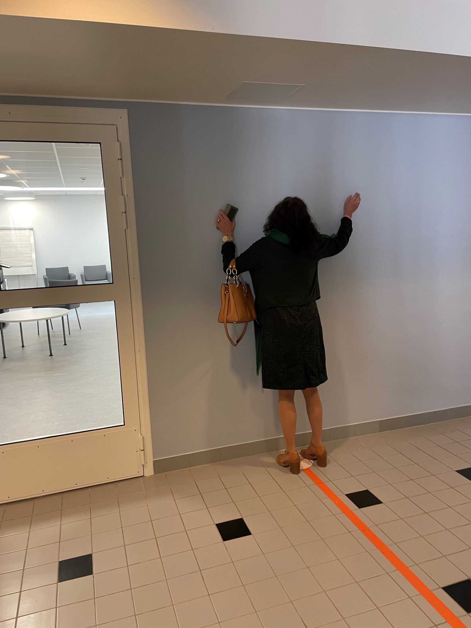 Kuvassa kuvityskuvana nainen on kävellyt näkövammaisille tarkoitettua toimistotiloissa lattiaan piirrettyä viivaa pitkin ja törmännyt seinään. Viiva päättyy seinään. 