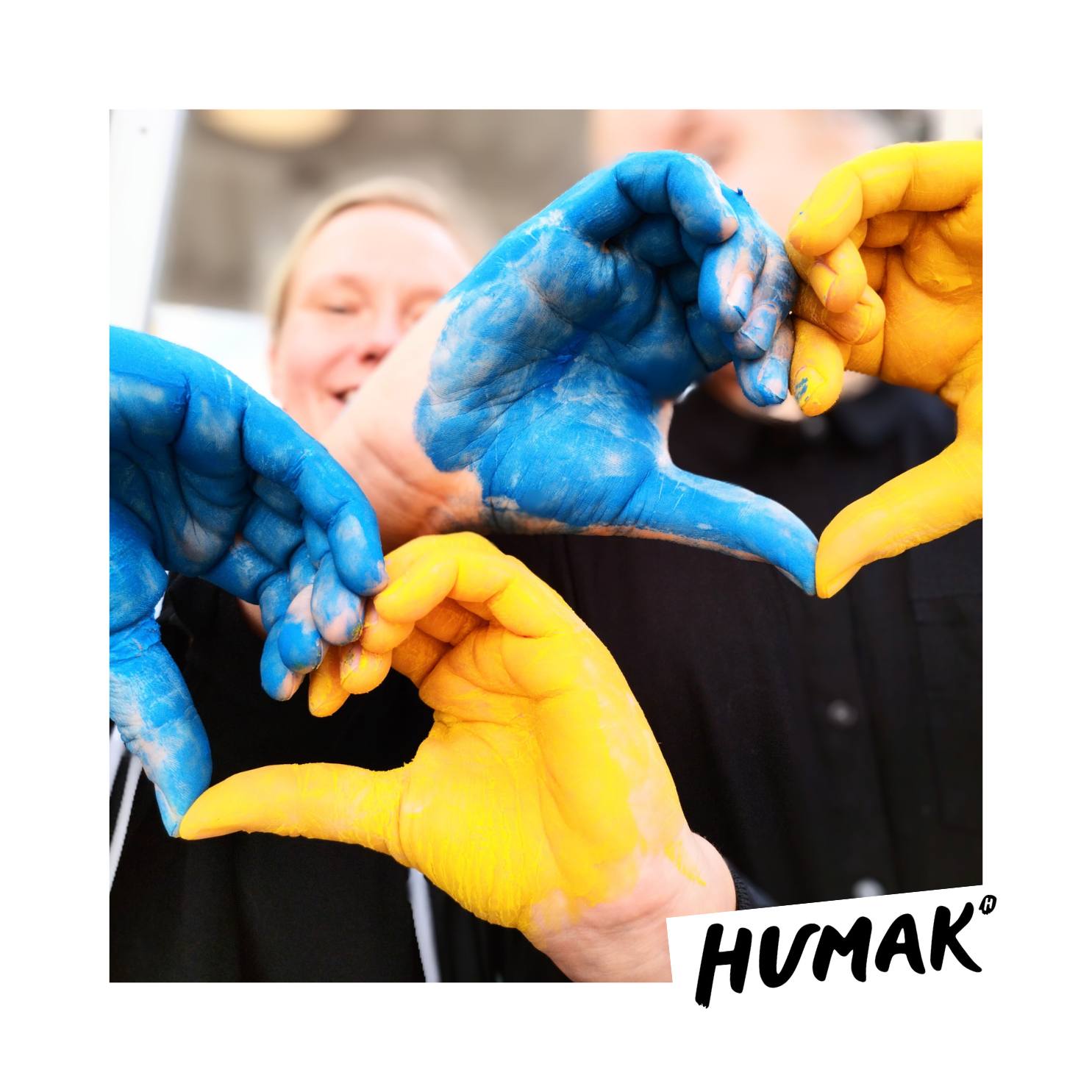 Kuvassa on kaksi käsiparia, jotka muodostavat sormilla sydämen. Kädet on maalattu Ukrainan lipun väreihin sinisiksi ja keltaisiksi.