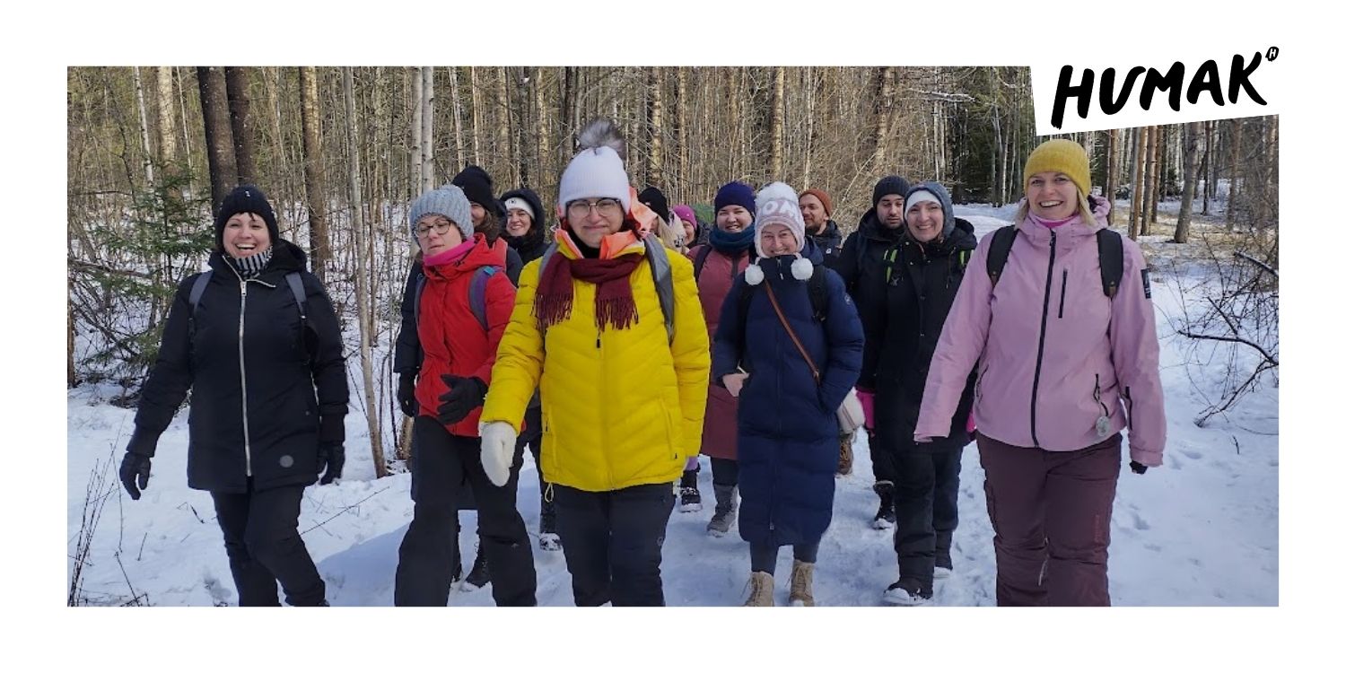 Kuvassa hymyileviä opiskelijoita kävelee ryhmässä talvisessa maisemassa. 