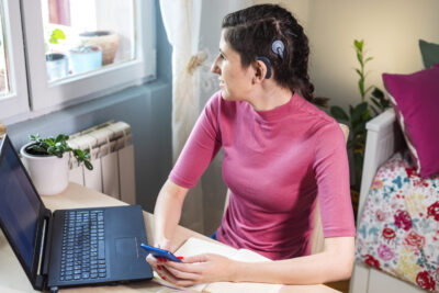 Young woman with cochlear implant studying at home.For better learning results she using modern technology.