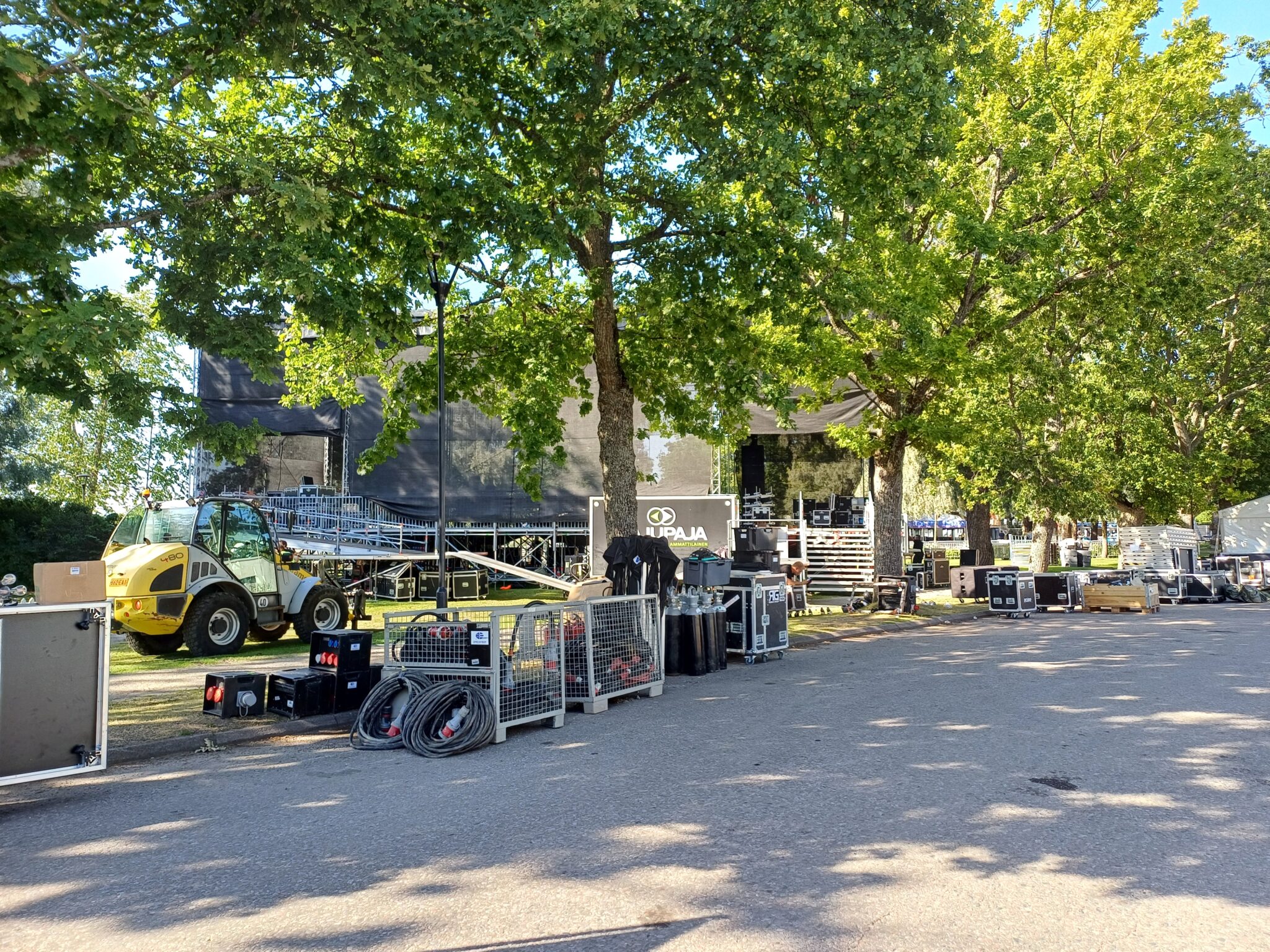 Tapahtuma-aluetta ollaan rakentamassa. Tien reunassa on paljon tavaroita ja tekniikkaa siirrettävänä oikeille paikoille. 