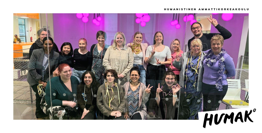 Joukko ihmisiä seisoo kahdessa rivissä ja hymyilee kameraan päin.