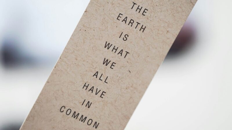 Sumeaa taustaa vasten paperikaitale, jossa teksti: The Earth is what we all have in common. Kuva: 2h Media, Unsplash.