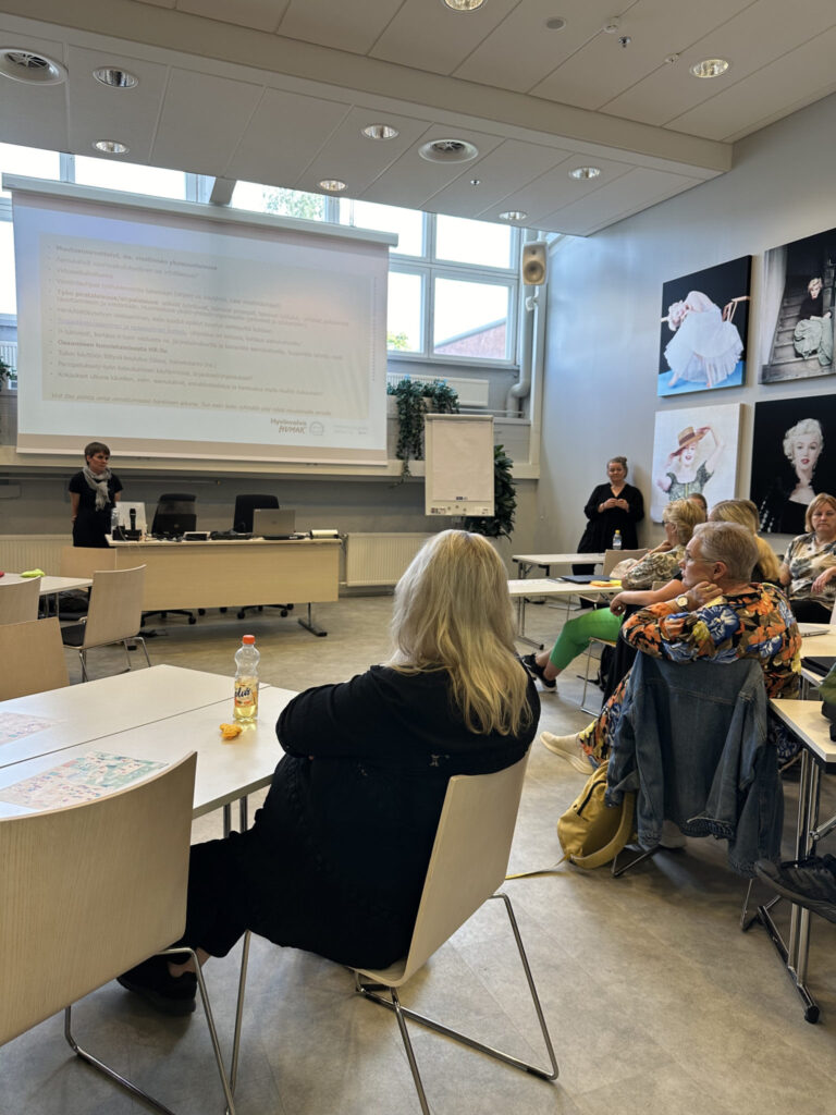 Opetustilassa Humakin henkilöstön jäseniä katselee kankaalle heijastettua PowerPoint-esitystä, jota projektipäällikkö Jenny Honka esittelee.