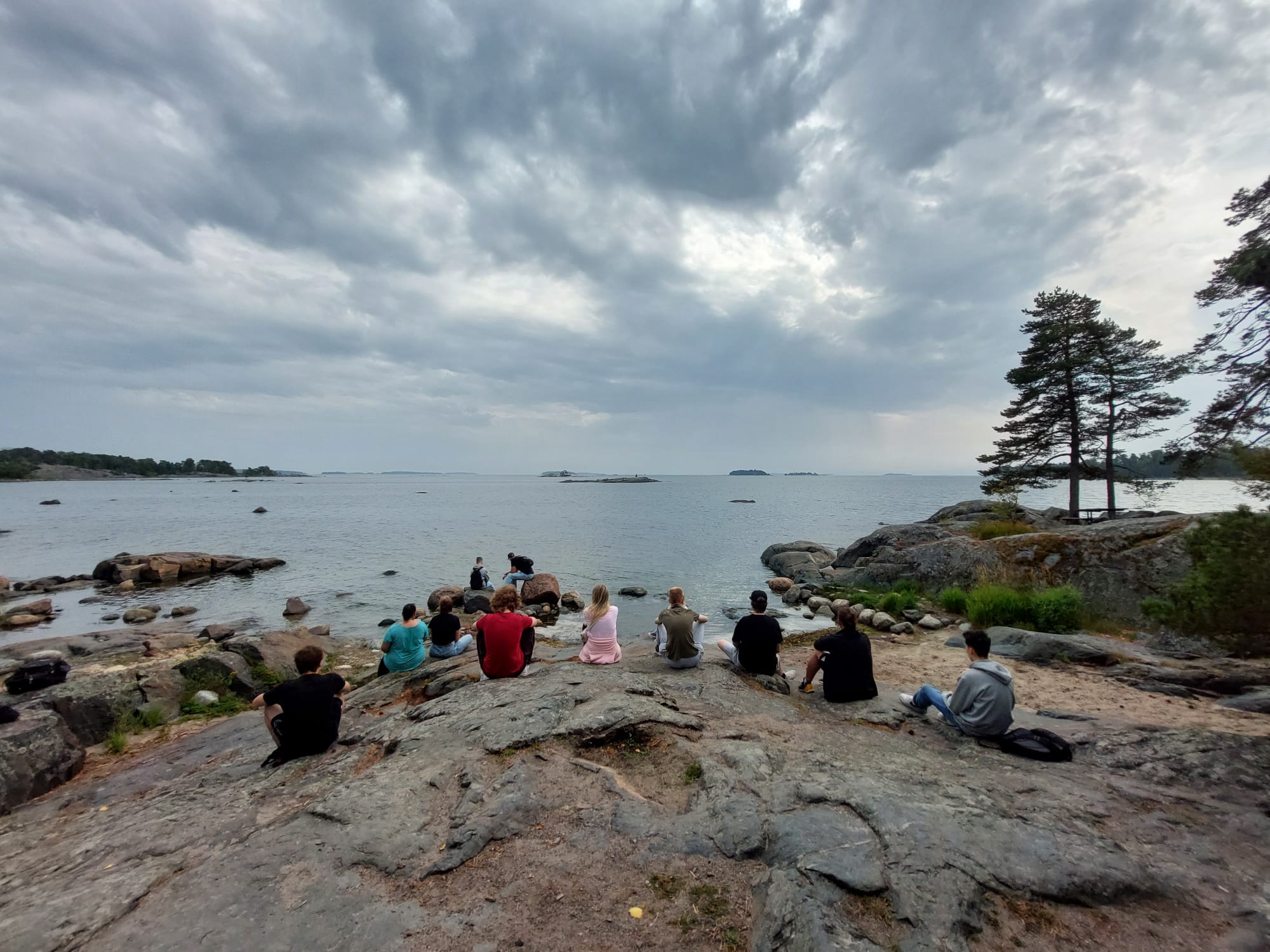 Nuoria istumassa kalliolla rannalla.