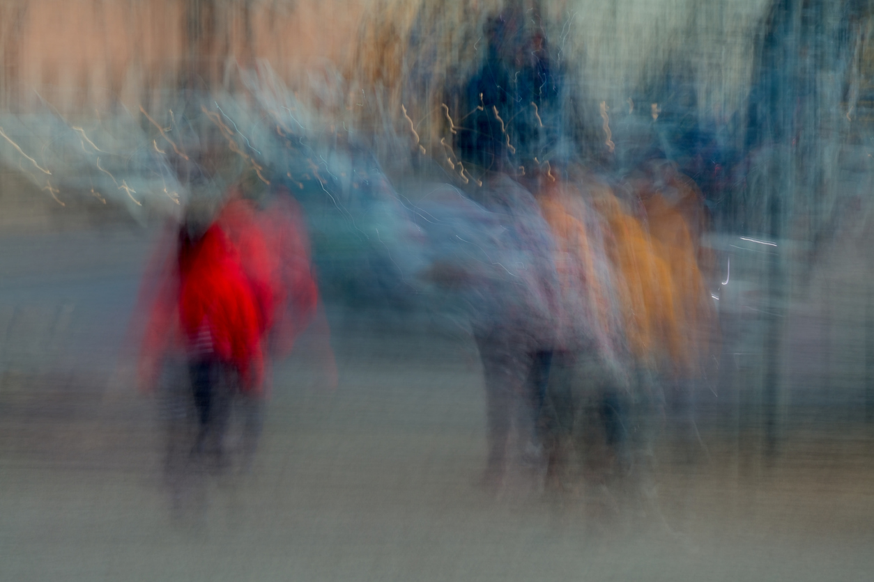 Abstrakti, liikkeestä sumentunut valokuva useista kävelevistä ihmisistä, joiden punainen, oranssi ja harmaa takki erottuvat kuvasta. Kaupungin taustavalot näkyvät utuisina juovina.Abstract of people waiting for traffic lights to change captured using ICM intentional camera movement technique, Helsinki, Finland.