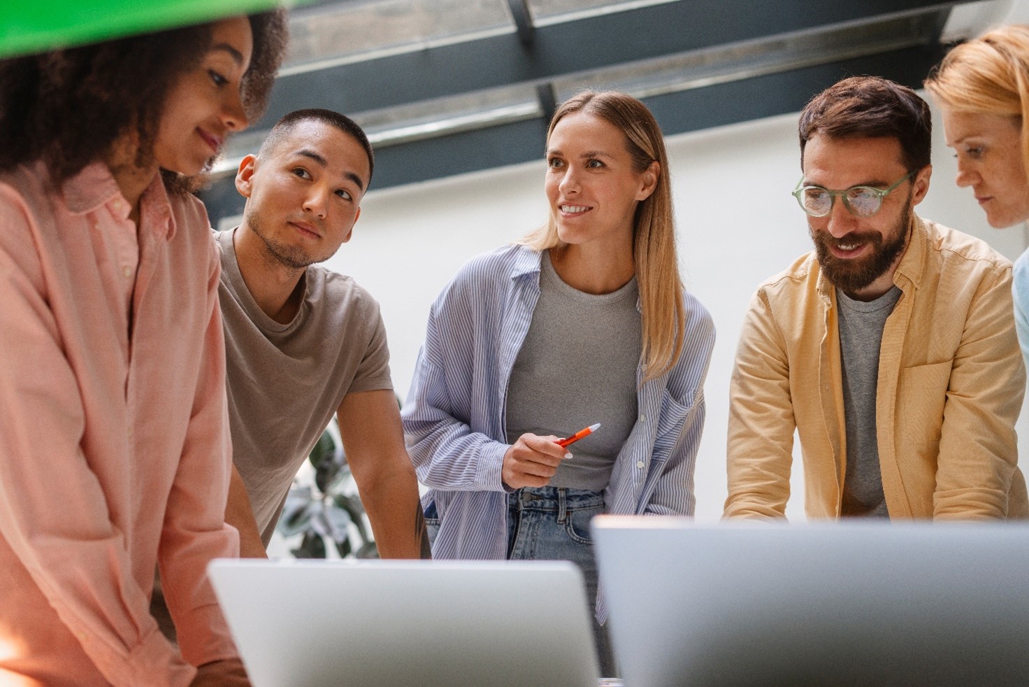 Erilaisia ihmisiä työskentelemässä yhdessä tietokoneen äärellä
