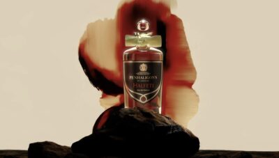 Keskellä hajuvesipullo, taustalla absrakti kuvio.