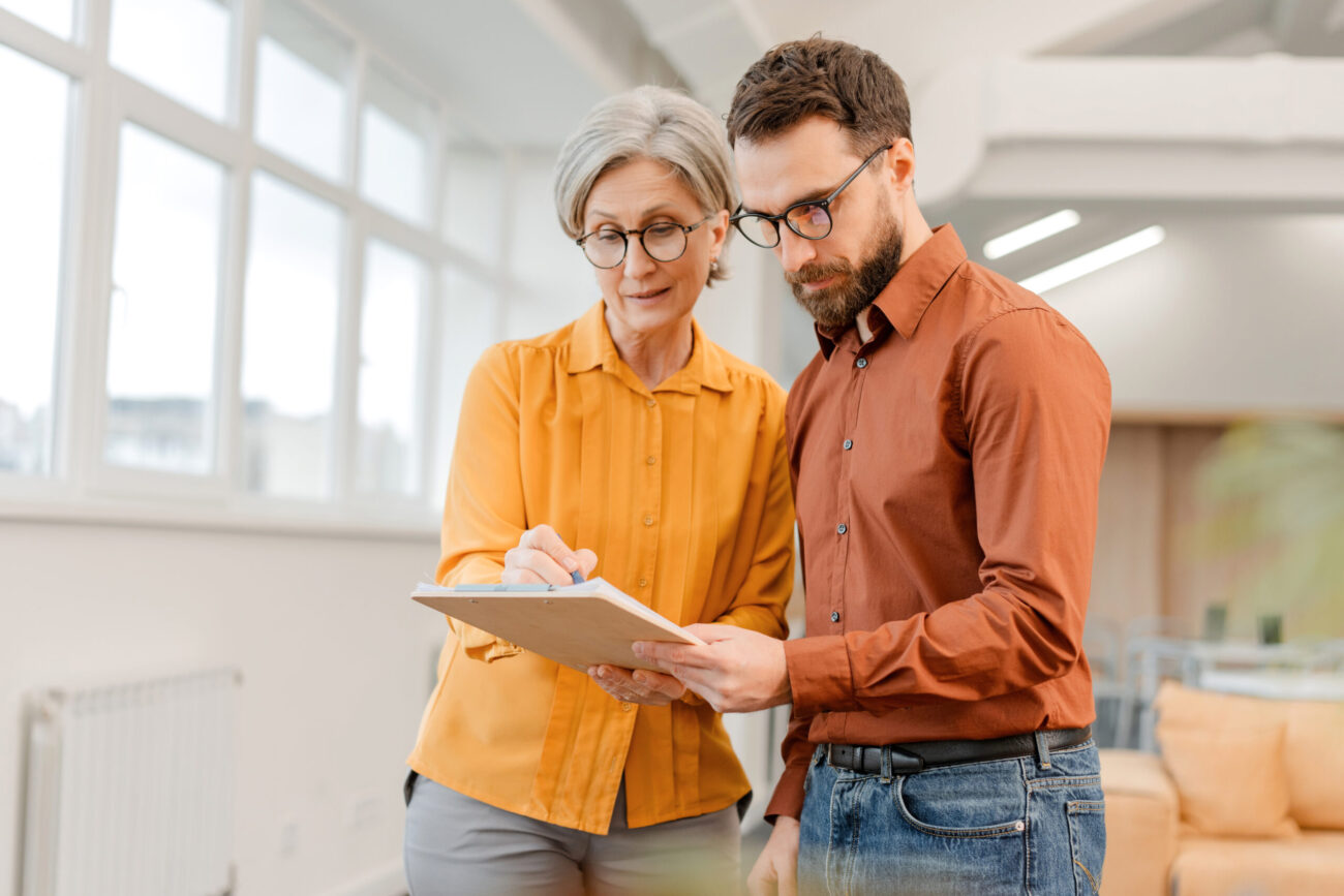 Business people, successful colleagues communication, brainstorming, sharing ideas, planning startup. Senior woman and man working together in modern office. Meeting, teamwork, successful business