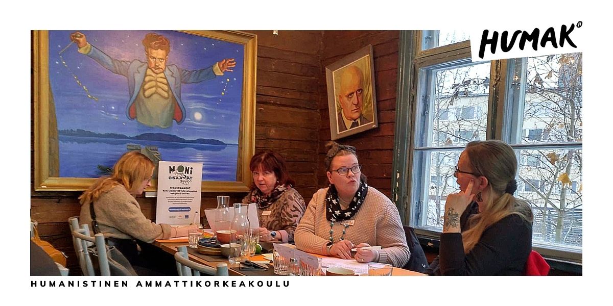 Neljä ihmistä kahvittelee pöydän ääressä hirsimökkimäisessä tuvassa. Seinillä on kaksi maalausta: Jean Sibelius nuorena ja Jean Sibelius vanhana.