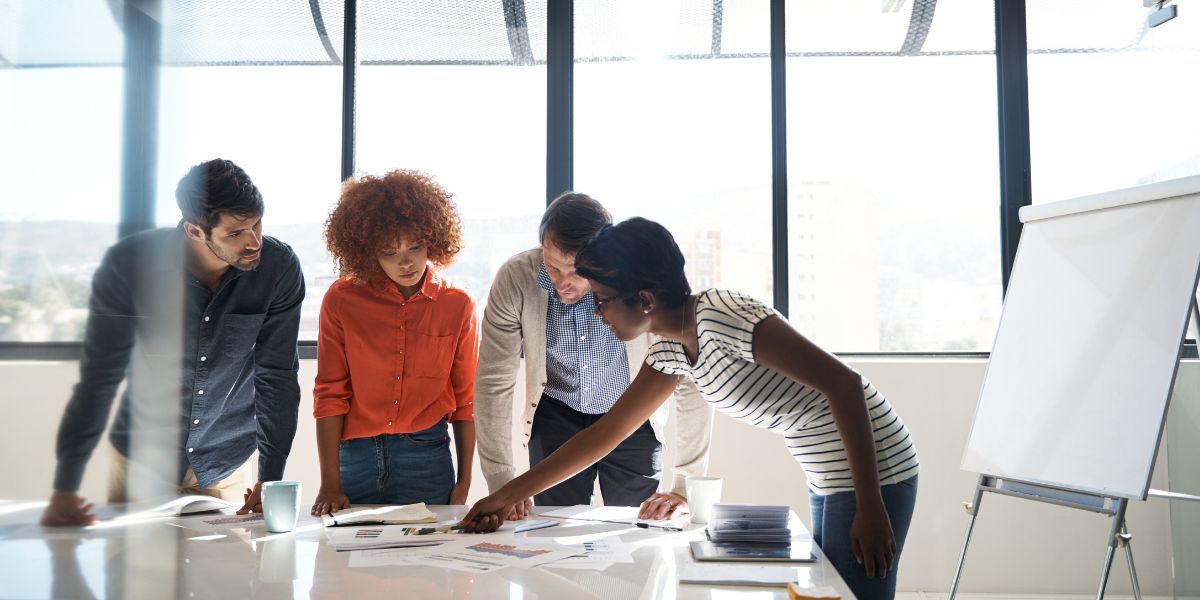 Group of people gathered around a table full of papers to discuss.