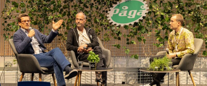 Kolme henkilöä keskustelee lavalla mikrofoneihin.