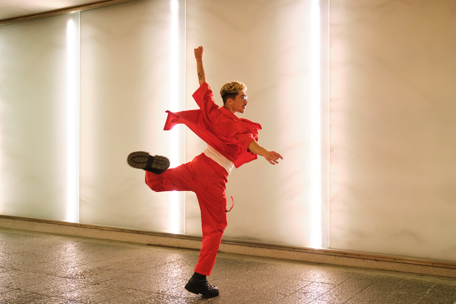 Punaisissa vaatteissa oleva henkilö tanssii kadulla.