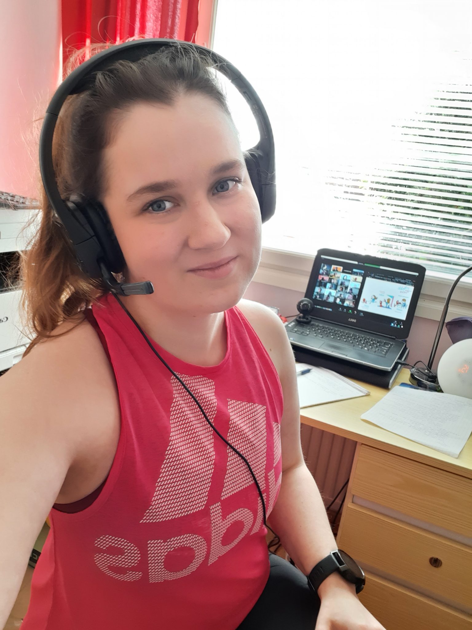 Tyttö istuu tietokoneen äärellä headset päässään.