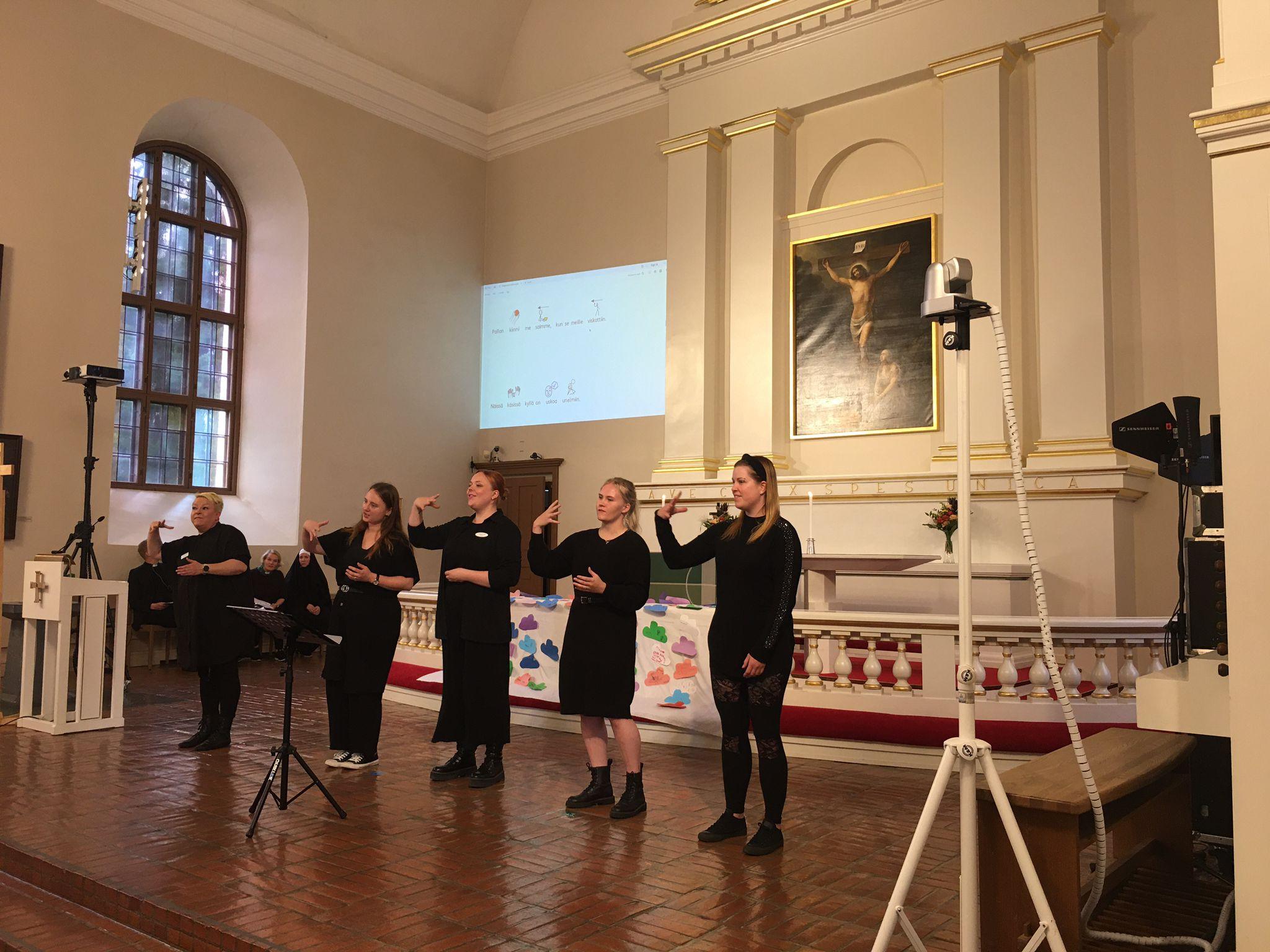 5 opiskelijaa tulkkaamassa kirkon alttarilla.