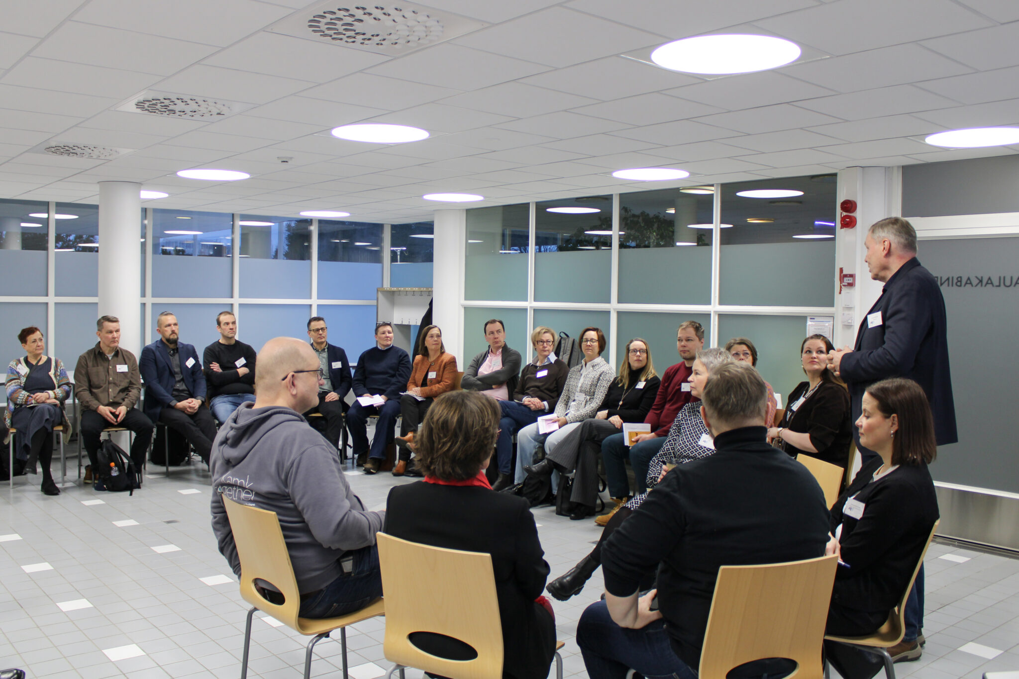 Joukko korkeakouluasiantuntijoita kokoontuneena yhteen. He istuvat puoliympyrässä. Ryhmän edessä puhuu Humakin rehtori Jukka Määttä.