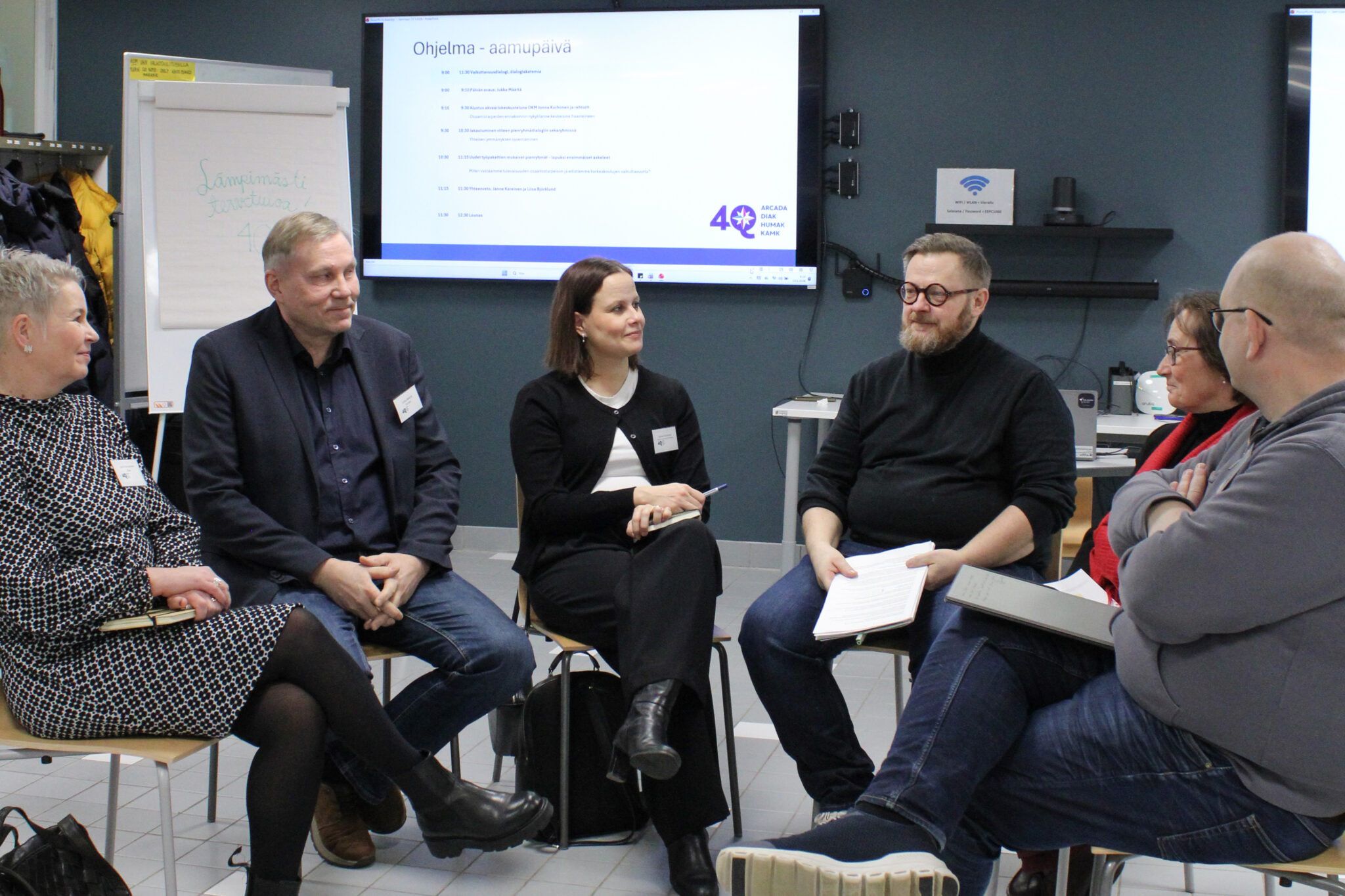 Kuusi ihmistä istuu Humakin neuvotteluhuoneessa puoliympyrässä. He ovat ammattikorkeakoulujen rehtoreita. He kuuntelevat vieraspuhujaa keskittyneenä.