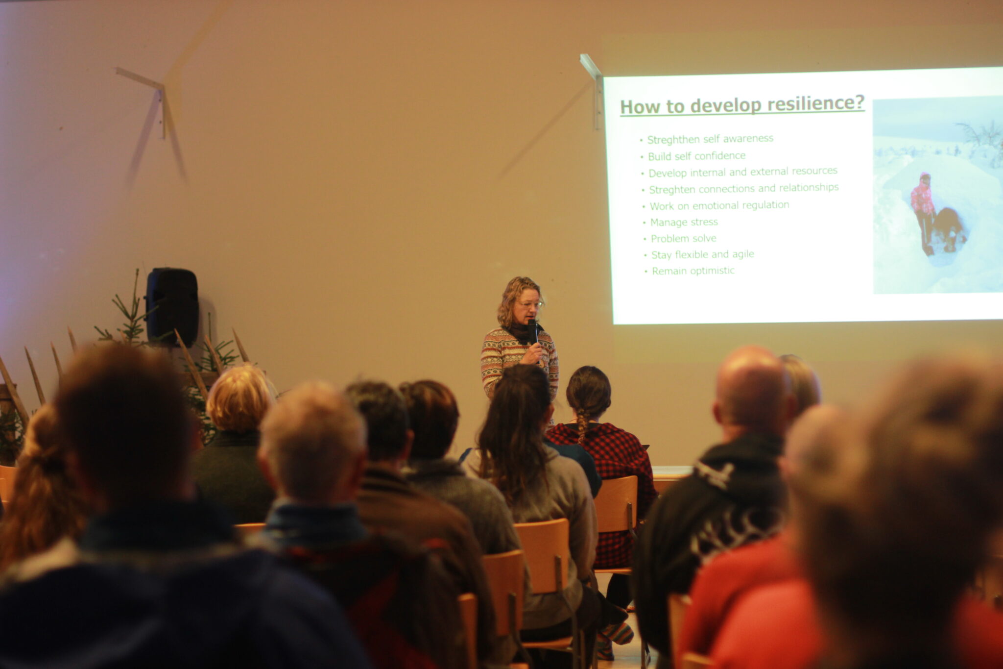 Woman giving a speech in classroom full of people.