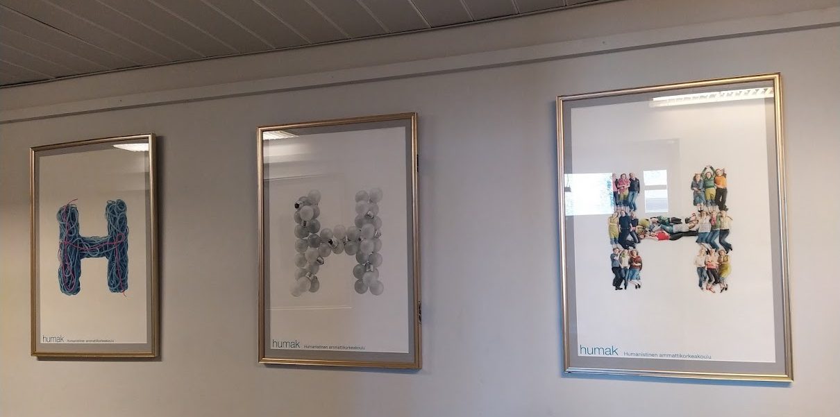 Seinällä kehystettyinä tauluina Humakin kolme erilaista H-kirjainta.