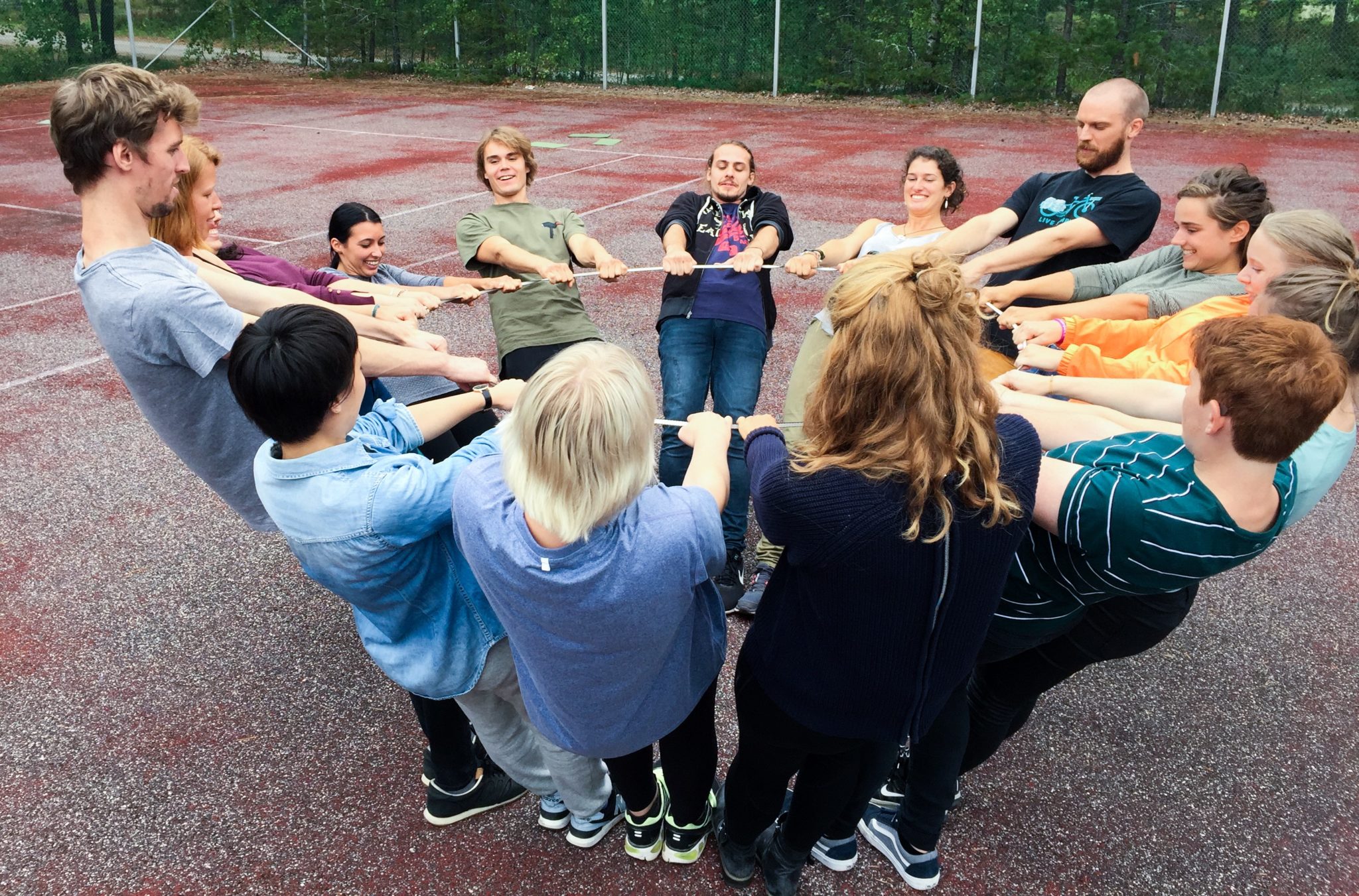 Opiskelijat ovat ympyrän muodostelmassa ja pitävät kiinni isosta renkaasta.