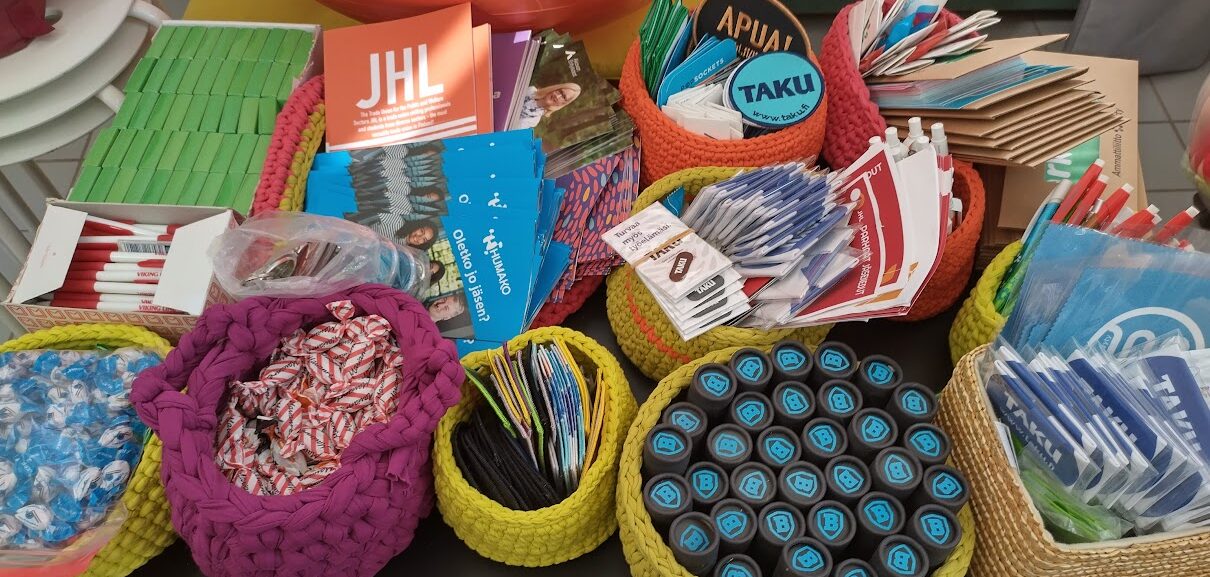 Kuvassa mainosmateriaalia HUMAKOsta, ammattiliitoista, kyniä, avainnauhoja, kyniä purkeissa. 