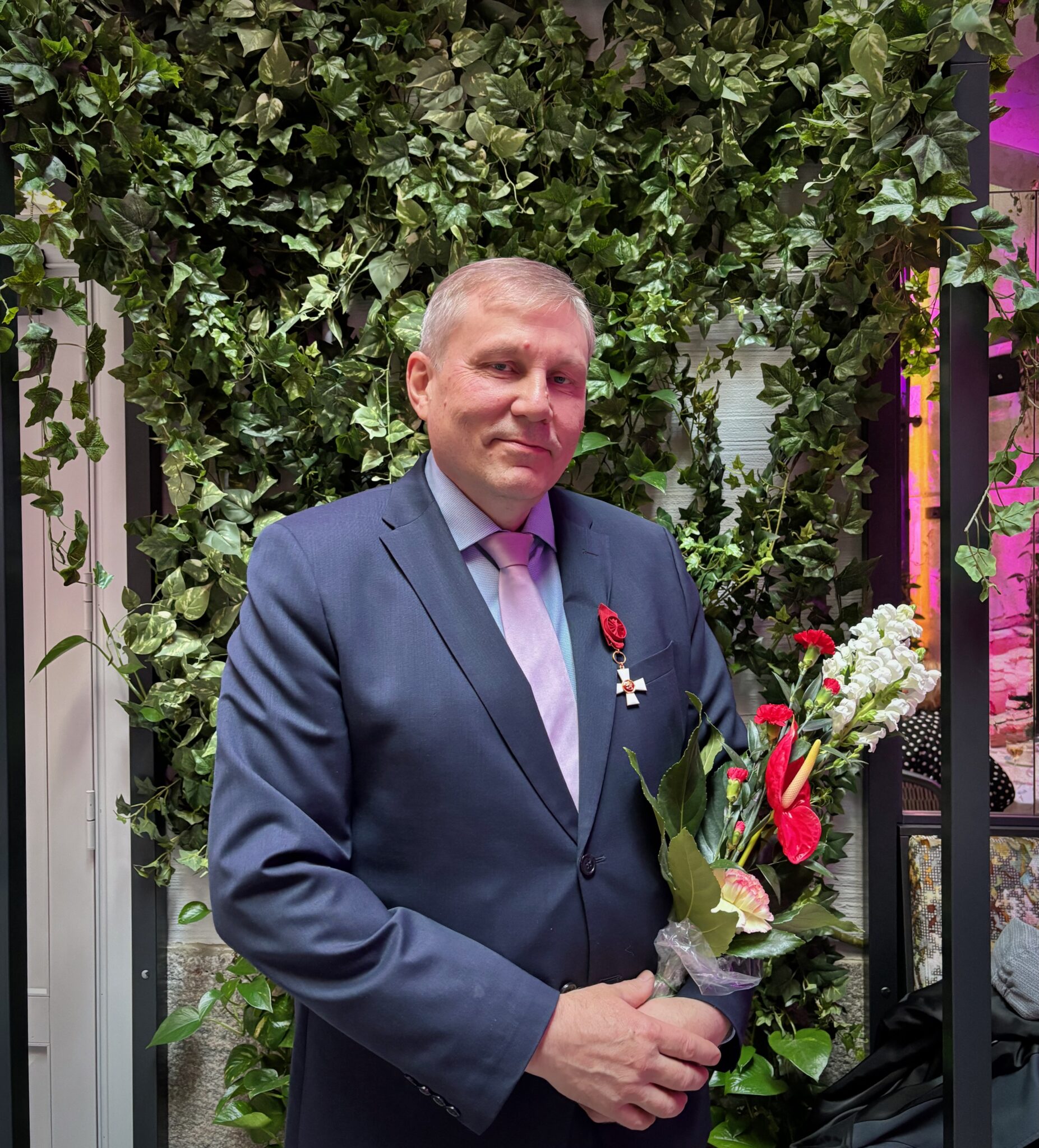 Jukka Määttä juhlatilaisuudessa, käsissä kukkakimppu ja rinnassa juuri luovutettu Suomen Leijonan I luokan ritarimerkki.