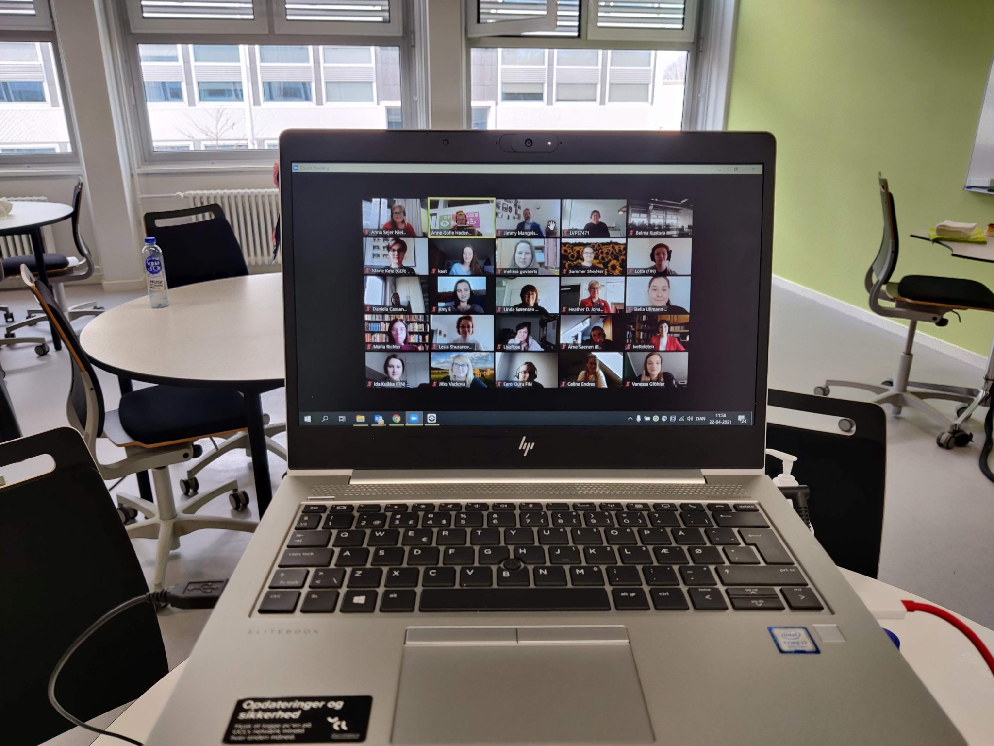 Kannettava tietokone jonka näytöllä Zoom-kokous jossa kymmeniä osallistujia.