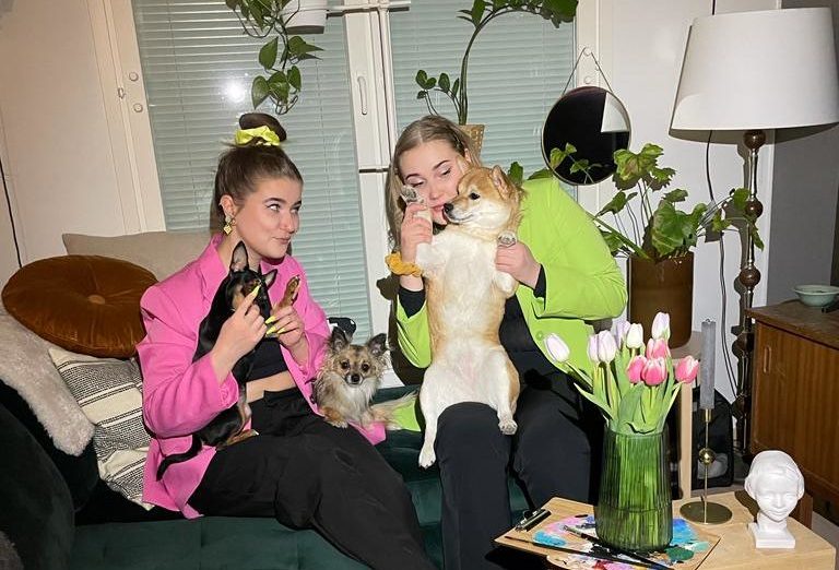 Linnea ja Marikki istuvat koirat sylissään.