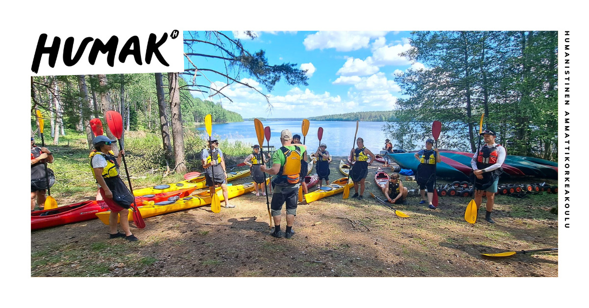 Humak students are standing by the shoreline, ready to learn kayaking skills.