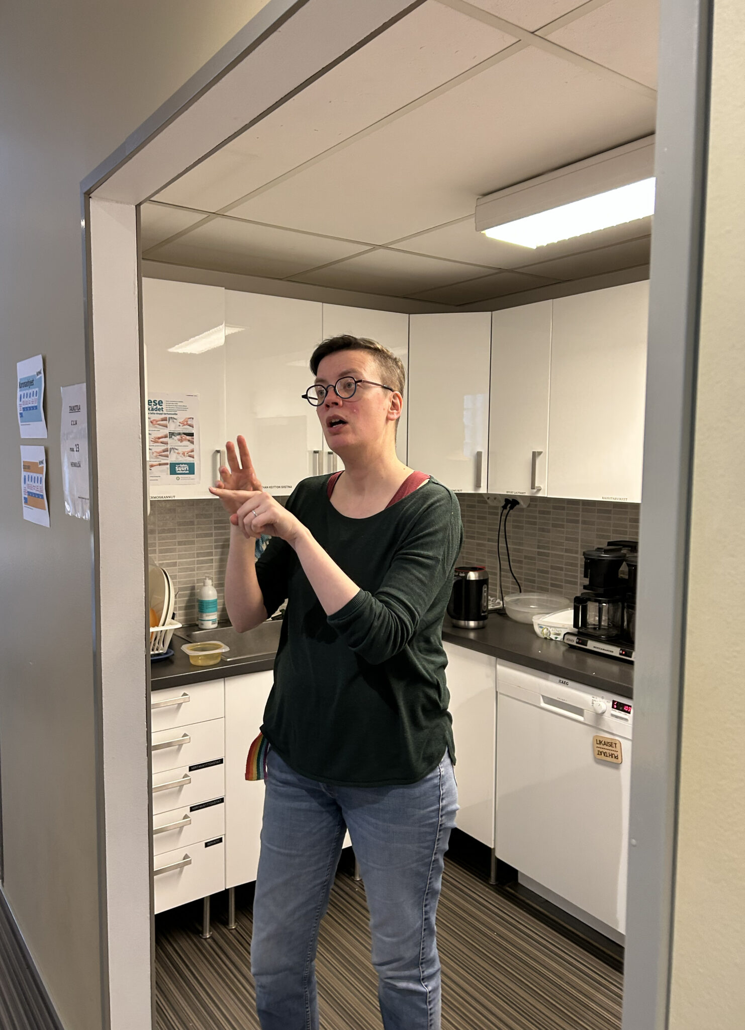 Henkilö seisoo keittiösyvennyksen ovella ja viittoo.