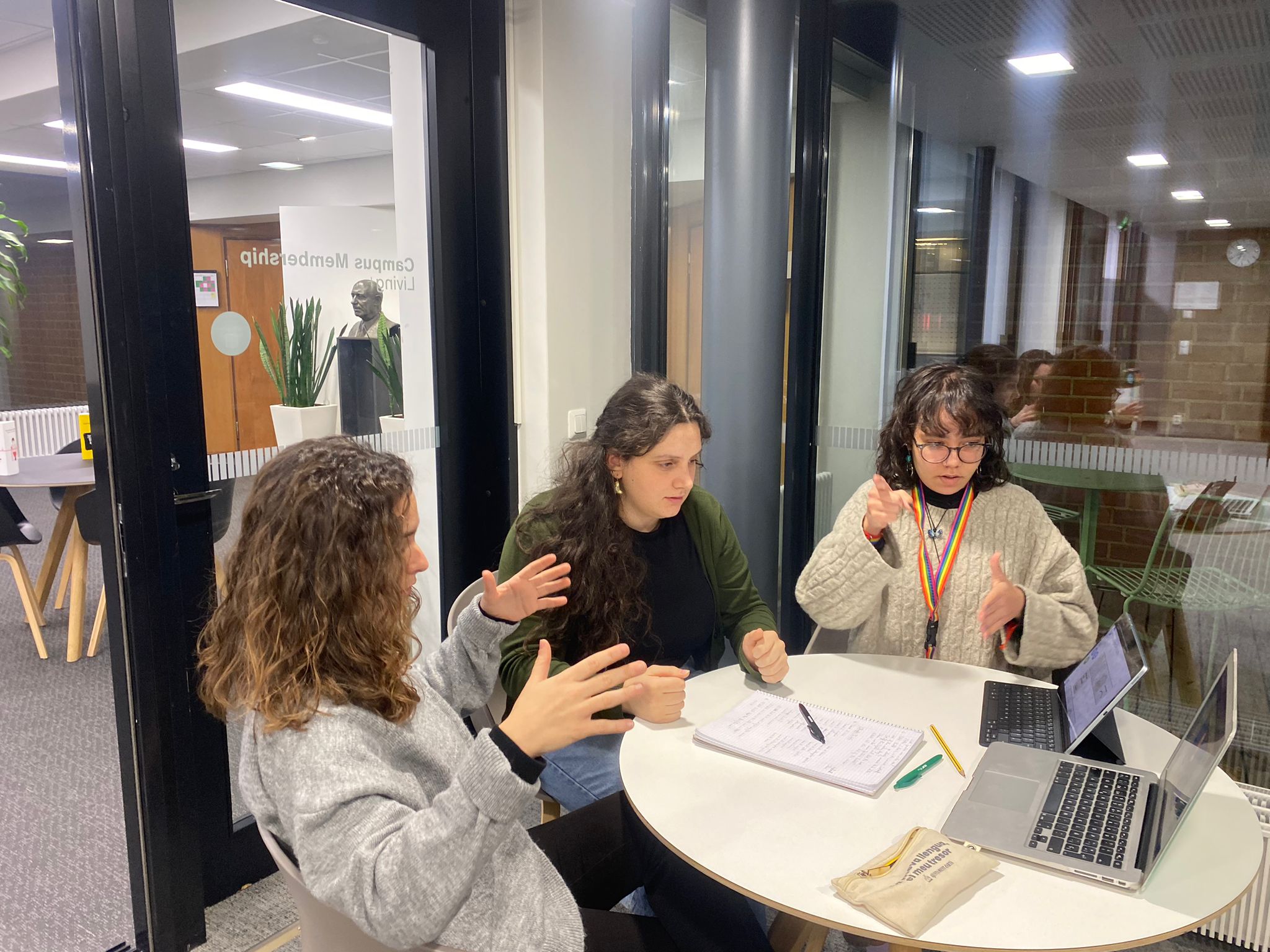 Kuvassa valkoisiin paitaan pukeutunut punahiuksinen nainen kuvattuna vyötäröstä ylöspäin. Kääntyneenä kameraan päin, mutta katse reilusti ohi kameran oikealle. Kasvoilla puhuva ilme ja kädet auki nostettuina kaulan korkeudelle. Musta tausta, lukuun ottamatta ihan naisen takana olevaa isoa pyöreää kohdevaloa.