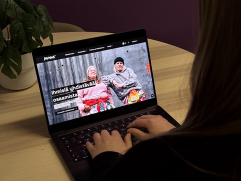 Humakin työntekijä katsoo kannettavalta tietokoneelta päivitetyn verkkosivun etusivua, jossa teksti: “Ihmisiä yhdistävää osaamista” ja kuva Humakin kahdesta opiskelijasta.