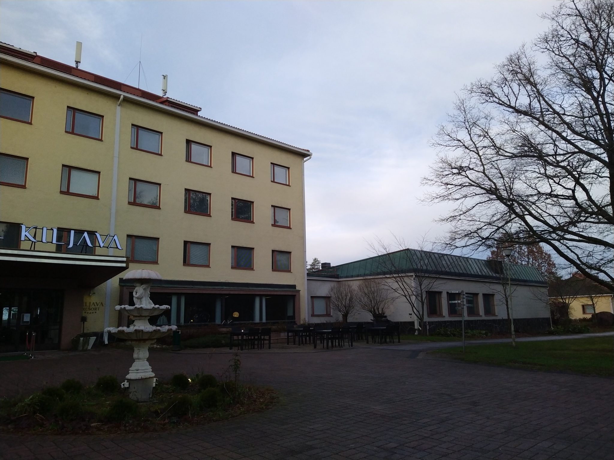 Nelikerroksinen, keltasävyinen majoitusrakennus, jossa paljon ikkunoita, teksti Kiljava oven päällä. Matalia sivurakennuksia kuvassa taaempana oikealla. Osa puuta, nurmikkoa, asfalttia ja ison rakennuksen edessä suihkukaivo.