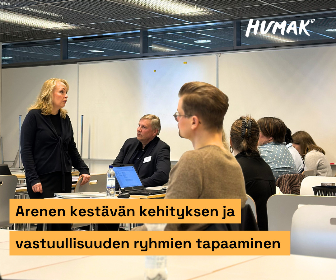 Ryhmä ammattikorkeakoulujen rehtoreita kuuntelee tarkasti puheenvuoroa. He istuvat luokkahuoneessa ja ovat pukeutuneet siististi. Yksi puhuja pitää puheenvuoroa muille. Hän seisoo pulpettien edessä.