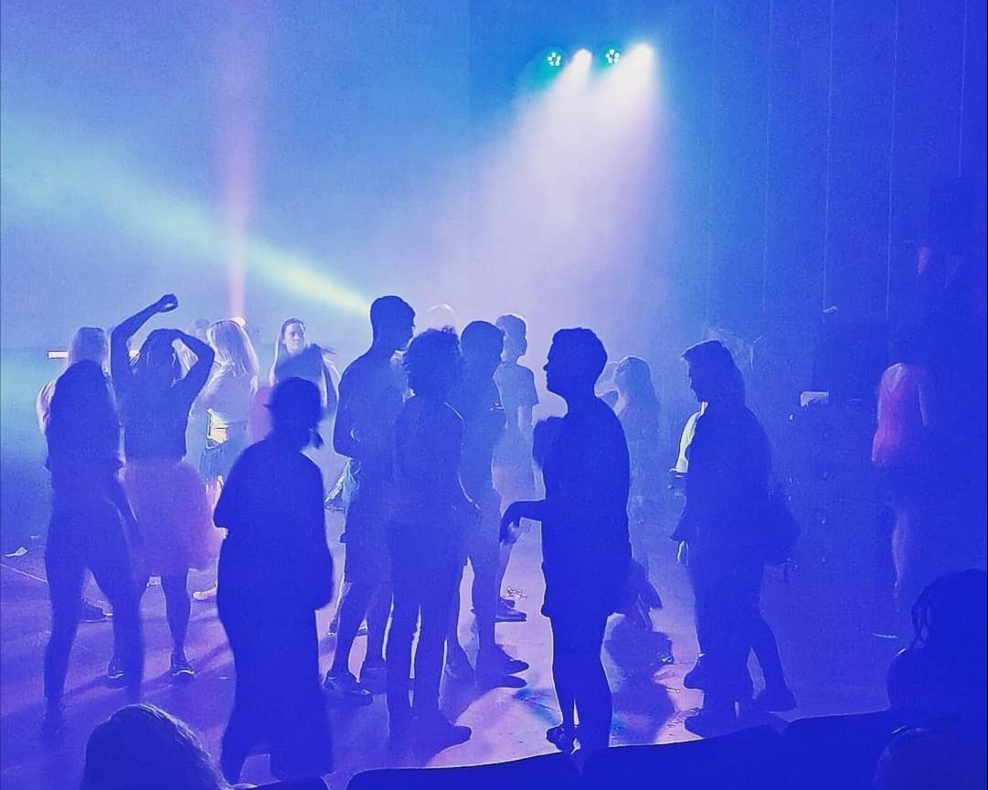 Sinisissä värivaloissa ihmisryhmä tanssii lattialla. 