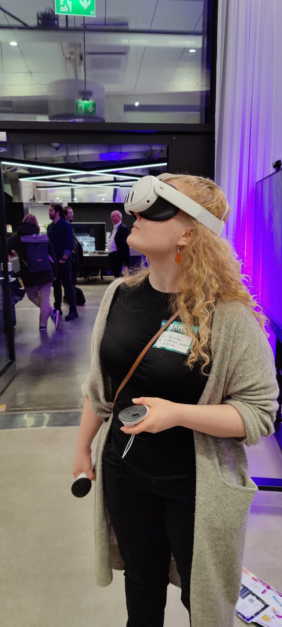 Ihminen katselee revontulia virtuaalilaseilla keskellä hektistä messutapahtumaa. 