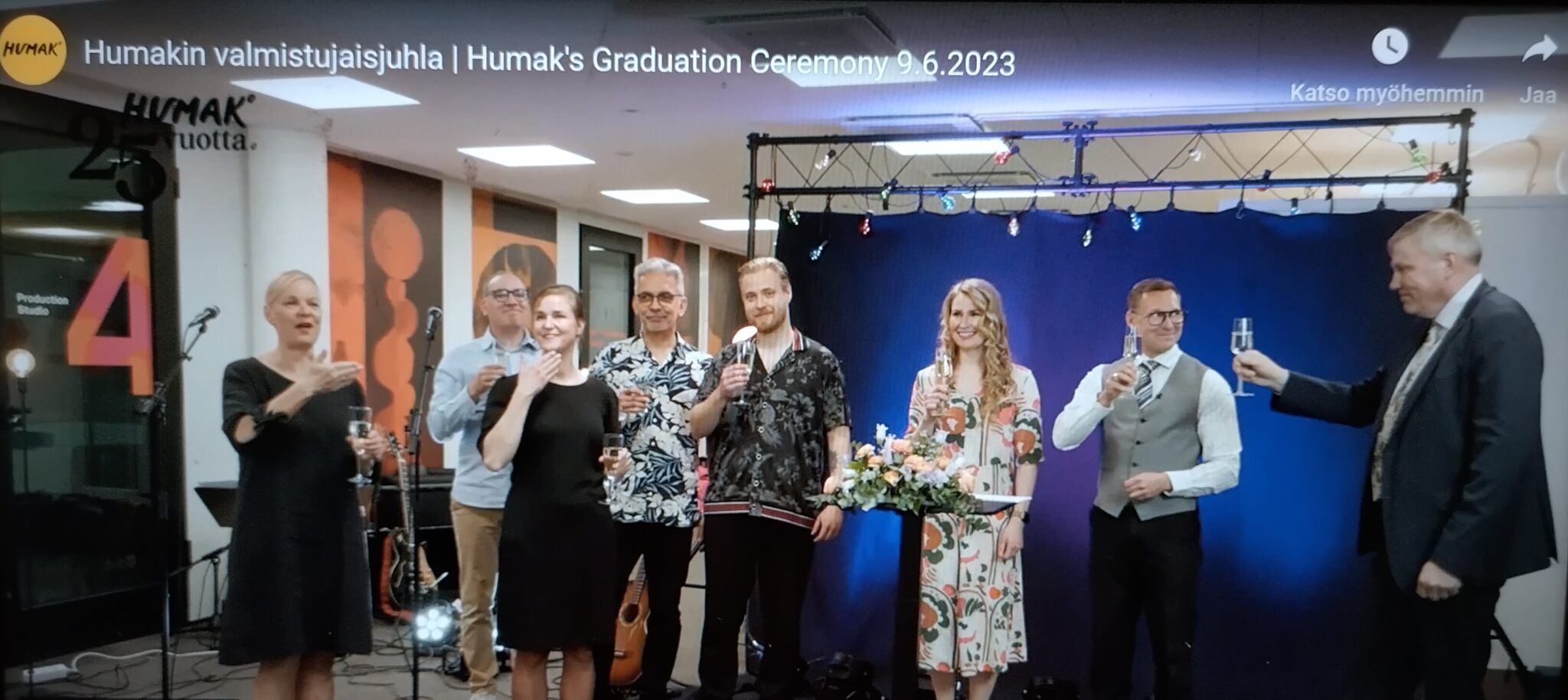 Kuvakaappauskuva youtubevideosta, jossa miehiä ja naisia juhlatunnelmissa skoolaamassa studio-tilassa. 