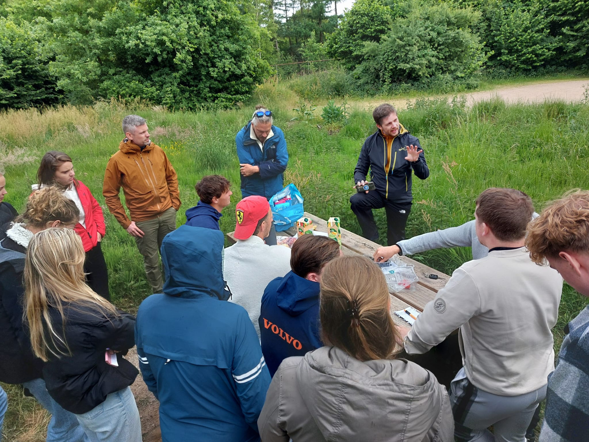 People standing in nature and listening Tero Lämsä's talk.