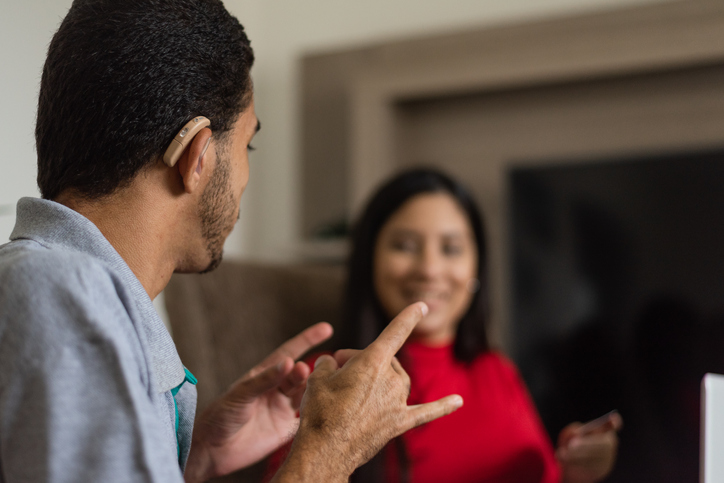 Deaf young people talking in sign language in the living room.