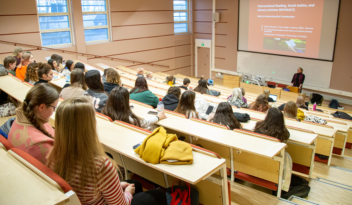 Auditoriossa ihmisiä istumassa ja kuuntelemassa esitystä.